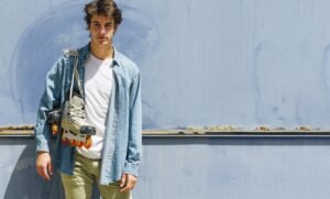 "Individual wearing a denim jacket layered over a spring outfit, standing outdoors amidst blooming surroundings."