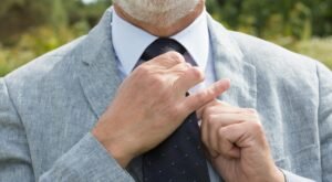"Man wearing a denim jacket over a shirt and tie, exemplifying a smart-casual outfit."