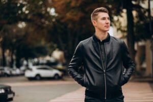 "Young man walking down a city street wearing black denim jeans and a casual outfit."