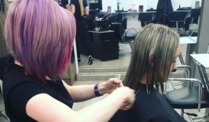 Woman cutting her hair in front of a mirror, considering a DIY wolf cut
