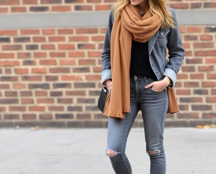 Woman wearing grey black jeans with a soft oatmeal sweater and beige accessories, styled for a cozy and elegant winter outfit. 