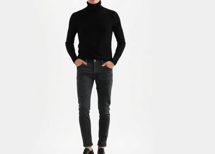 Woman wearing a cream silk turtleneck blouse tucked into blue denim jeans, posing stylishly in a minimalist setting.