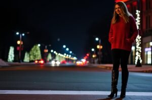 Woman wearing a red sweater dress paired with heeled boots, ready for an evening out